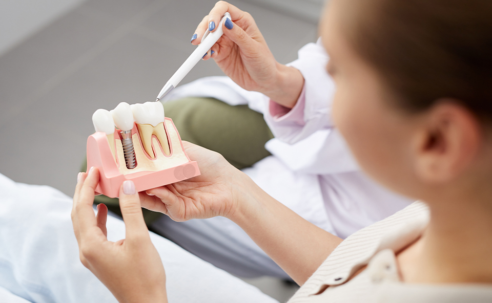 Higienistka stomatologiczna instruuje pacjenta, jak poprawnie dbać o higienę implant&oacute;w zębowych.